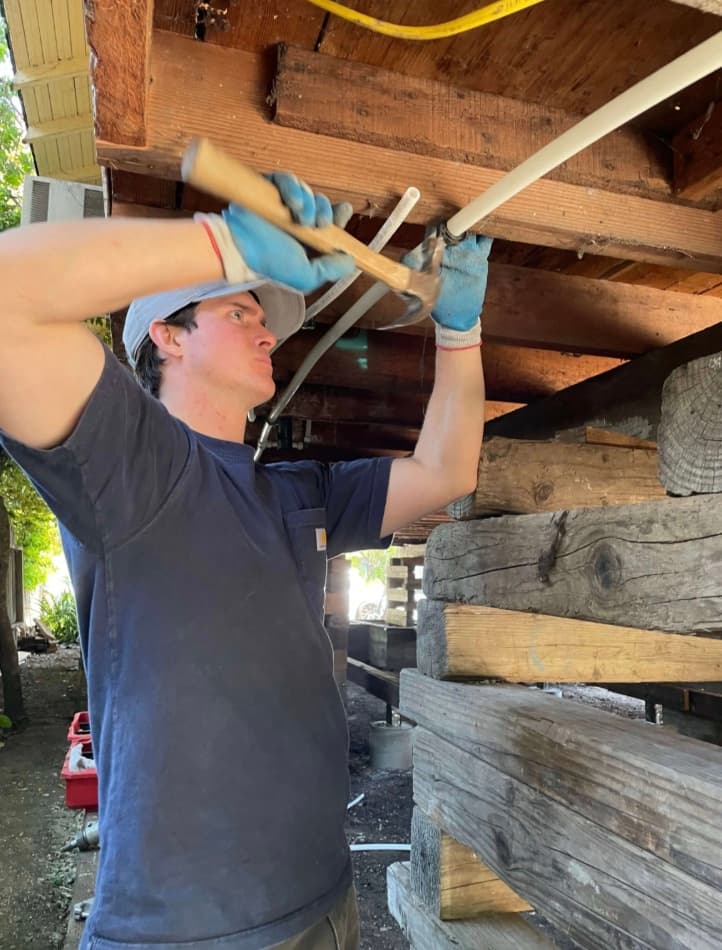 Plumber installing a new water supply line under a raised home in Sonoma County